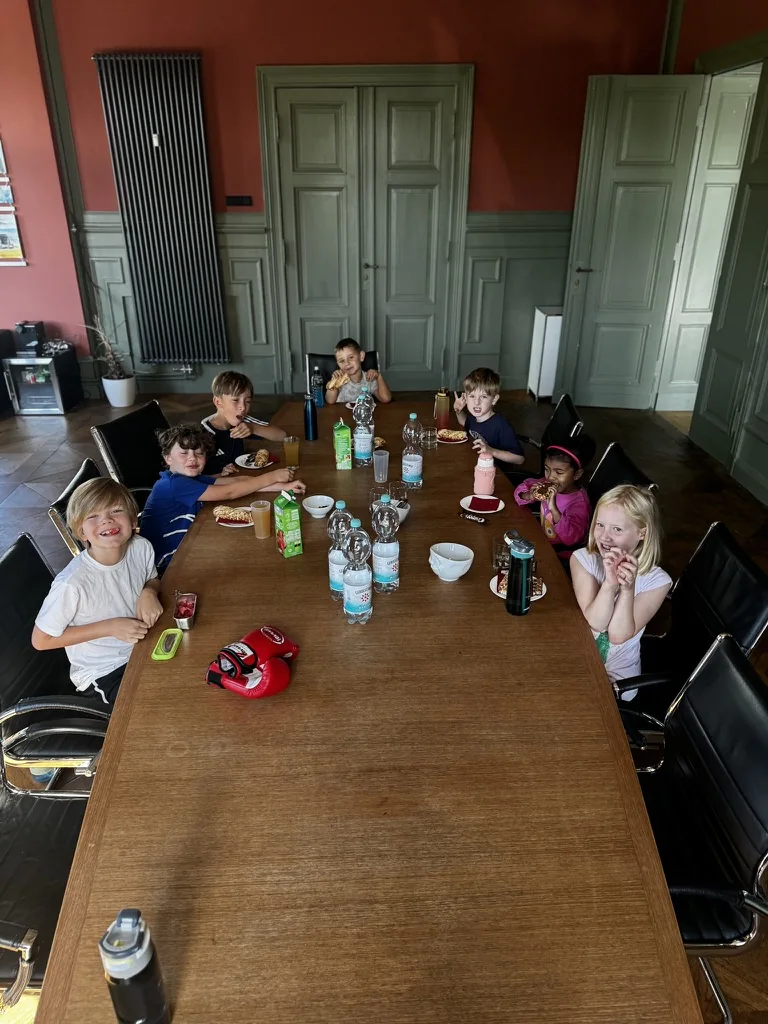 Kinder sitzen während einer gemeinsamen Pause am großen Tisch.